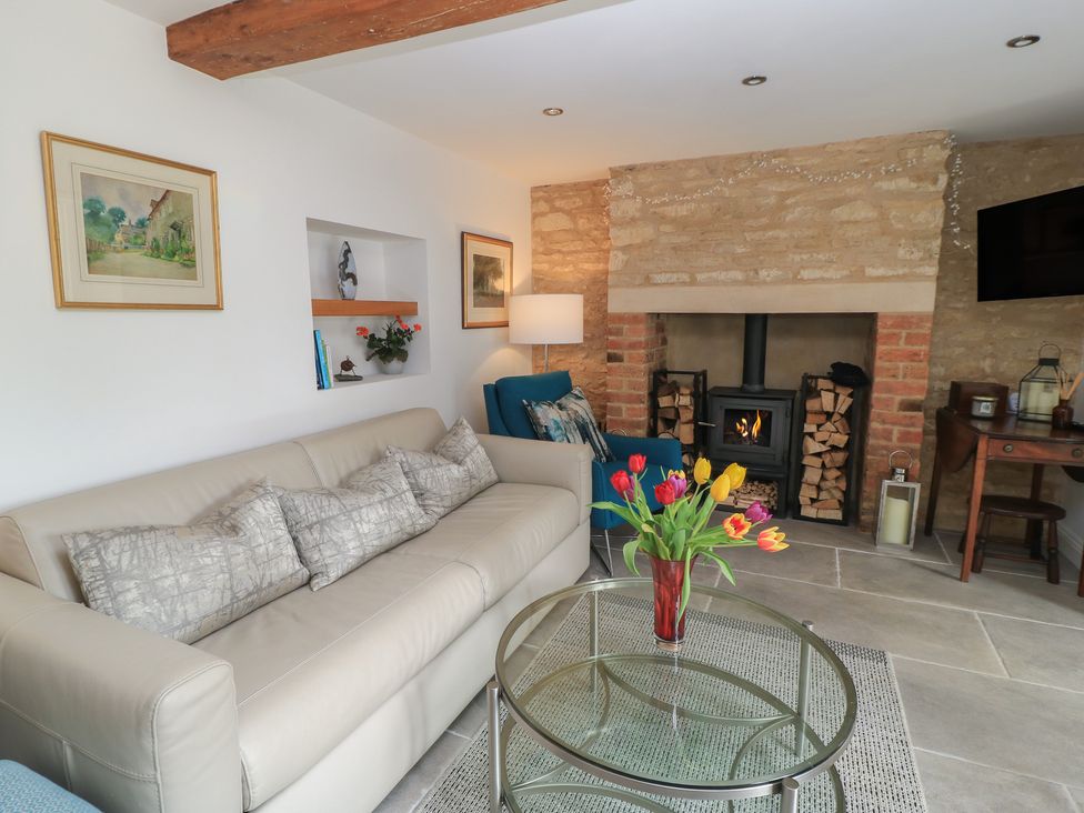 A living room with a fireplace and sofa at The Cottage in Ashton Keynes