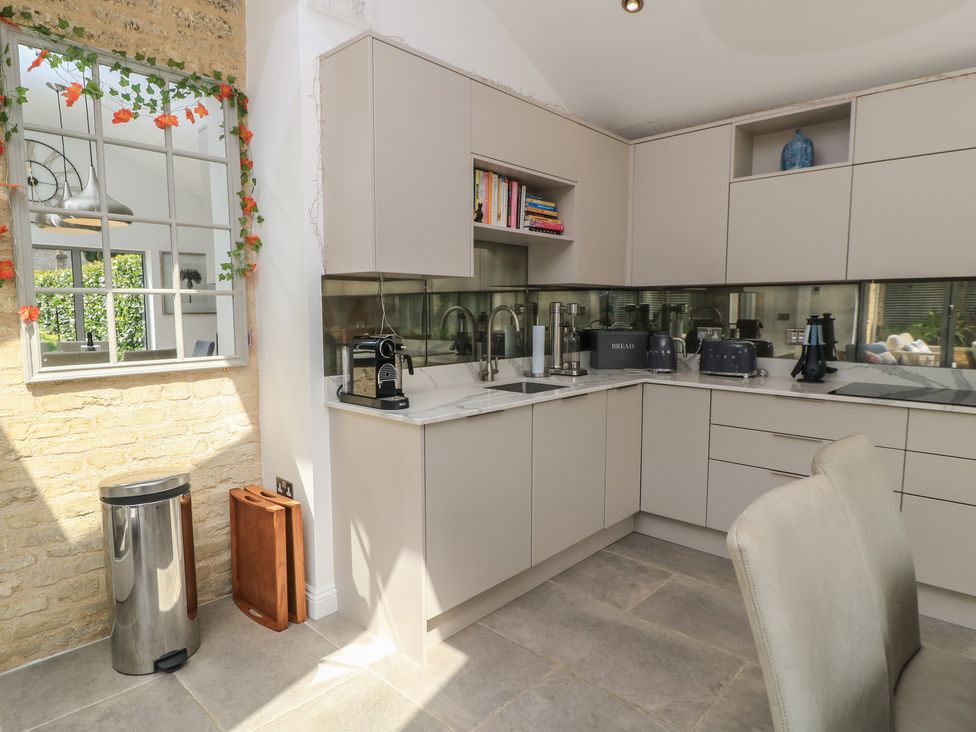 A kitchen with modern appliances and books at The Cottage in Ashton Keynes