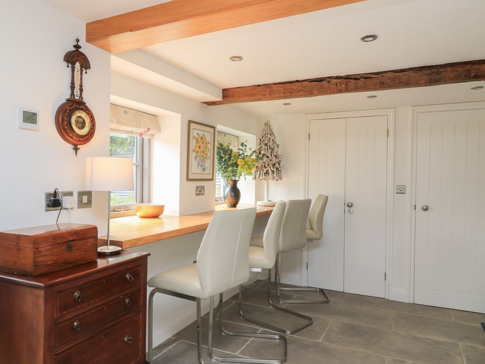 A kitchen with a countertop and bar stools at The Cottage in Ashton Keynes