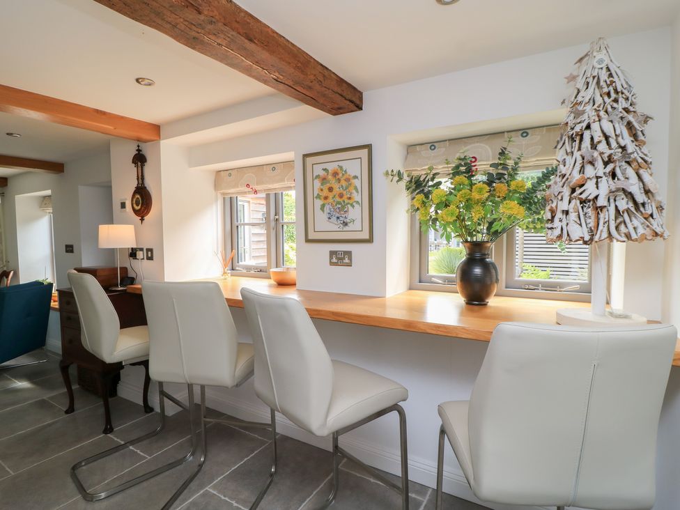 A kitchen with bar stools and a flower arrangement at The Cottage in Ashton Keynes