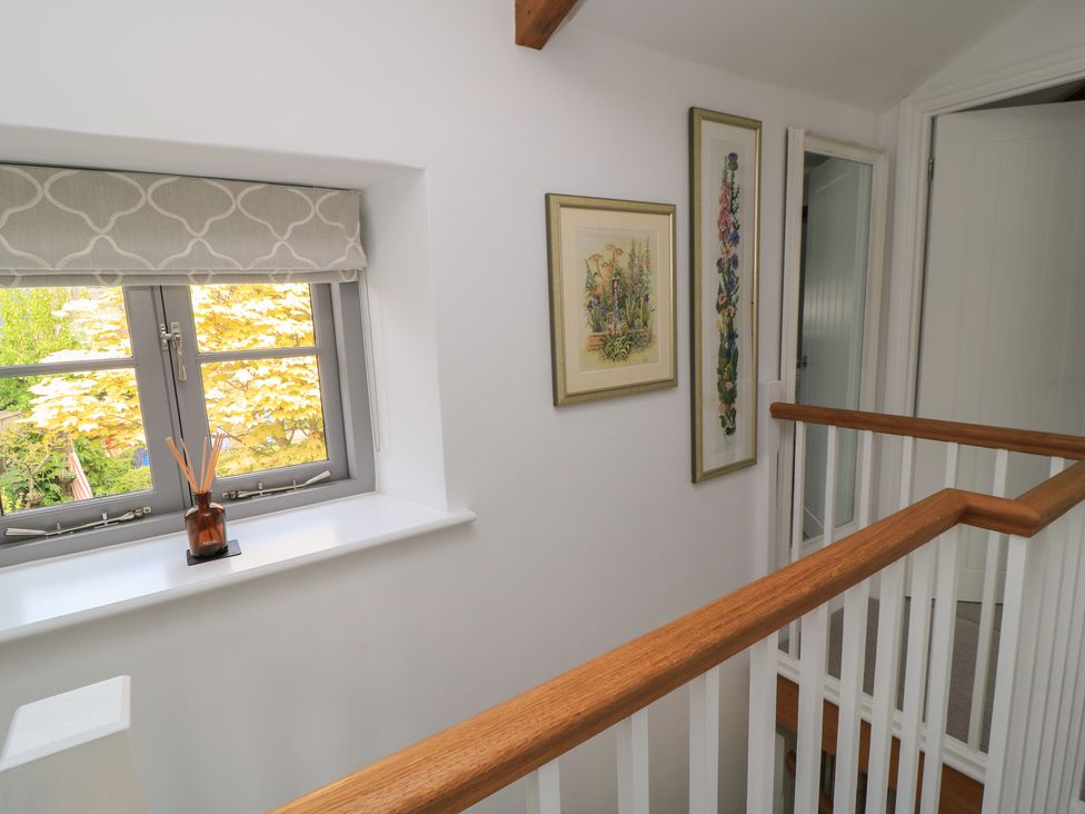 A hallway with a window and paintings at The Cottage in Ashton Keynes