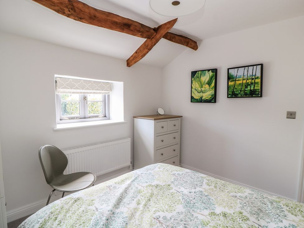 A bedroom with a bed and dresser at The Cottage in Ashton Keynes