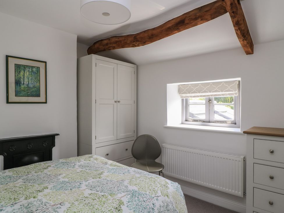 A bedroom with a bed, wardrobe, and window at The Cottage in Ashton Keynes