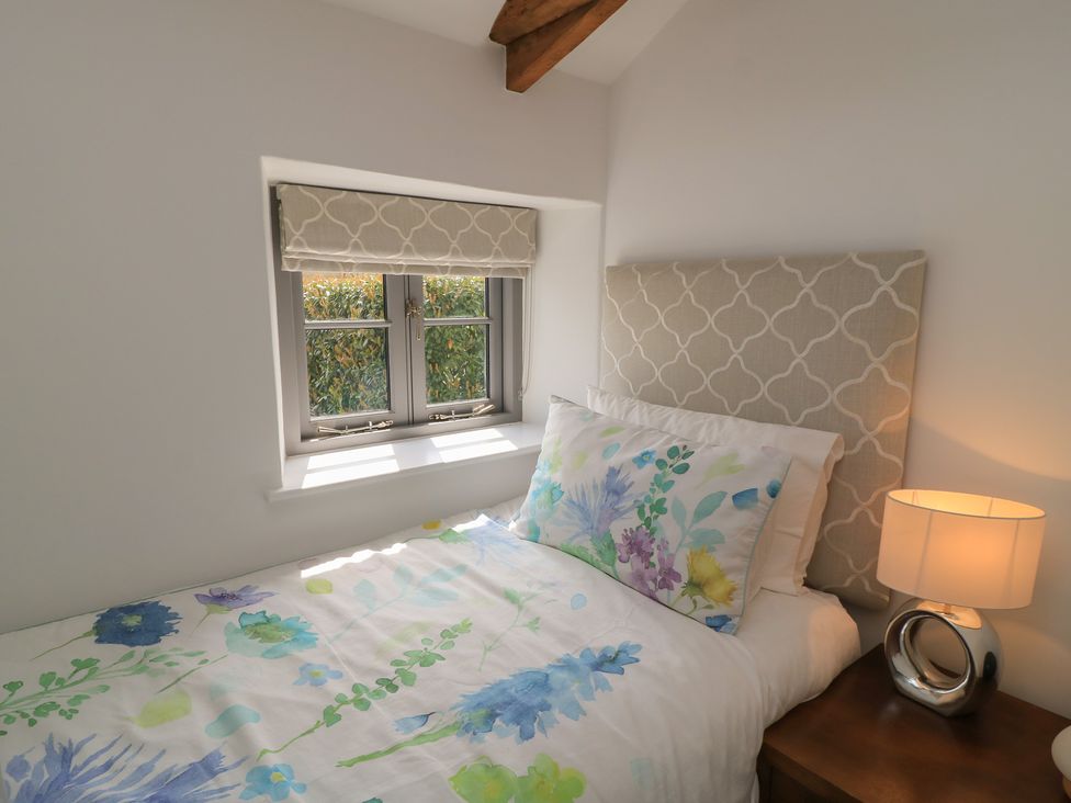 A bedroom with a bed and lamp at The Cottage in Ashton Keynes
