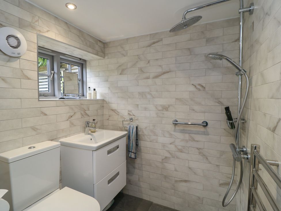 A bathroom with a sink, toilet, shower and window at The Cottage in Ashton Keynes