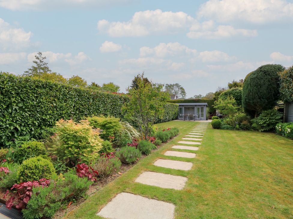 A garden with a pathway leading to a house at The Cottage in Ashton Keynes
