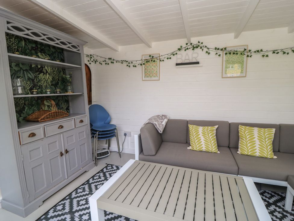A snug with a sofa, coffee table, and a sideboard at The Cottage in Ashton Keynes
