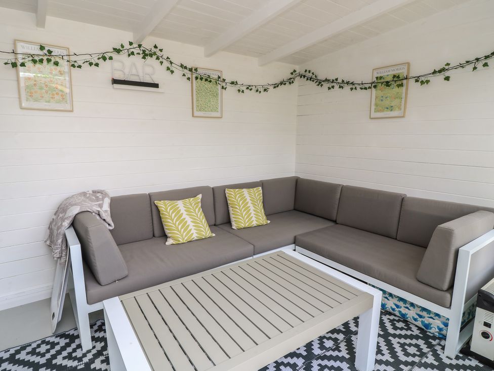 A snug area with a sofa, coffee table, and decorative items at The Cottage in Ashton Keynes