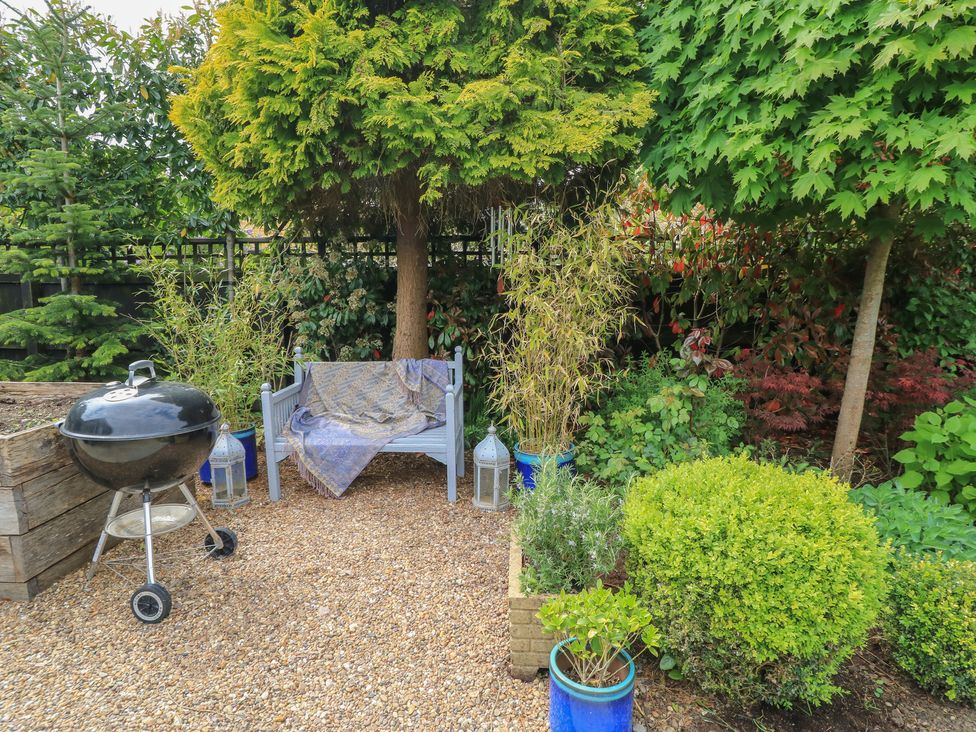 A garden with a bench, grill and plants at The Cottage in Ashton Keynes