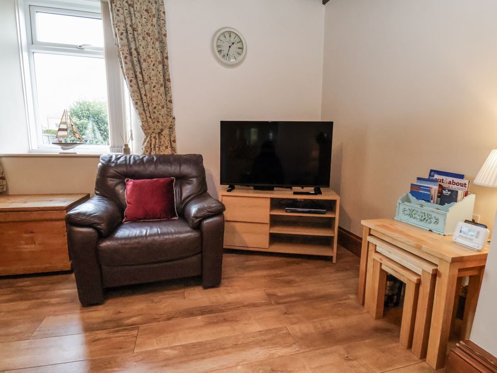 A living room with an armchair and a television at 2 High Stakesby Cottages in Whitby