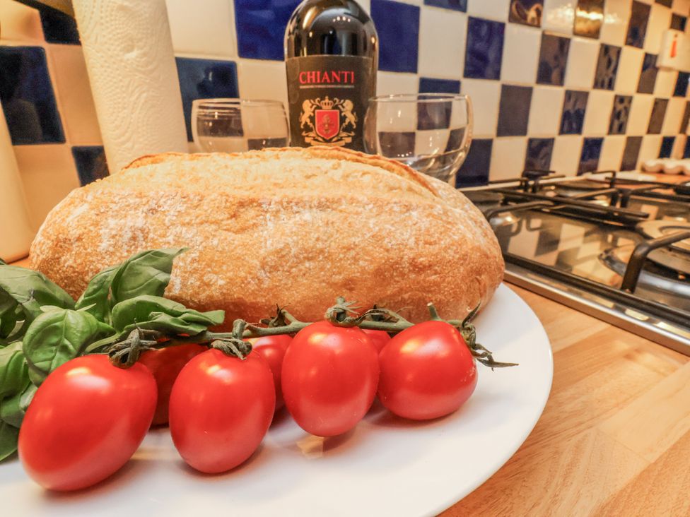 A kitchen scene with bread, tomatoes, basil, wine and glasses at 2 High Stakesby Cottages Whitby