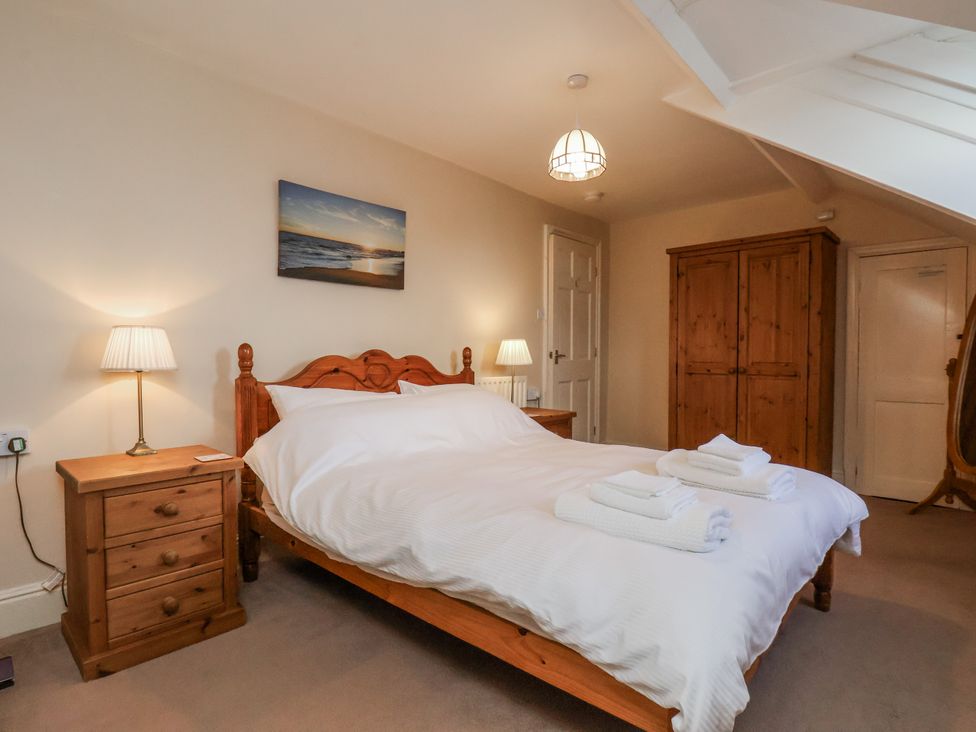A bedroom with a bed and wooden furniture at 2 High Stakesby Cottages, Whitby