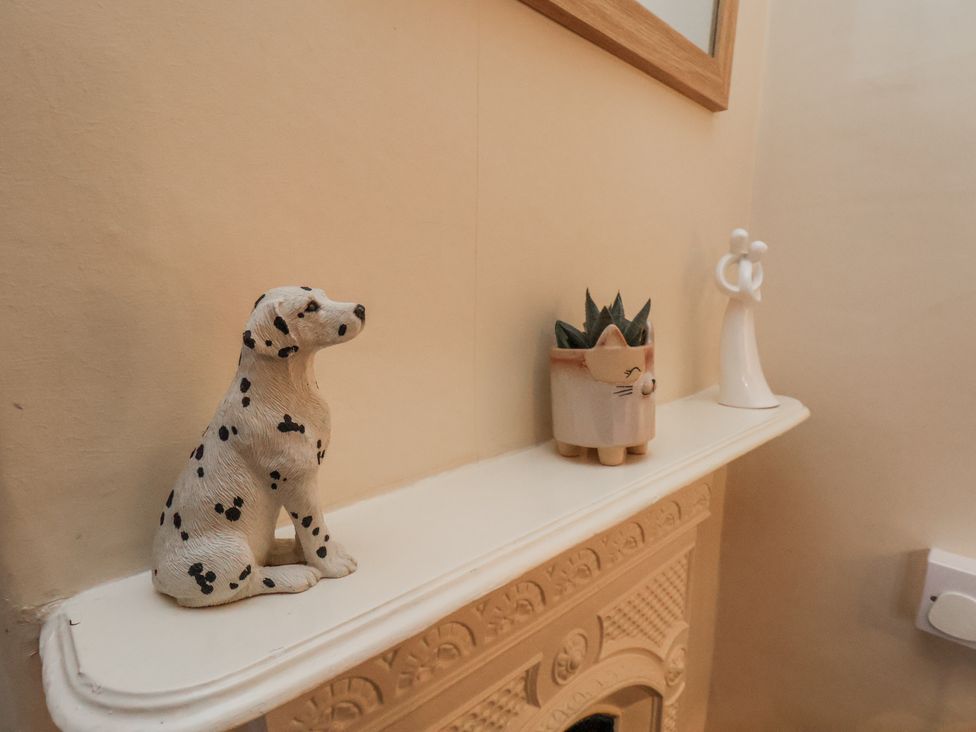 A mantel with a dog figurine, plant pot, and angel figurine at 2 High Stakesby Cottages, Whitby