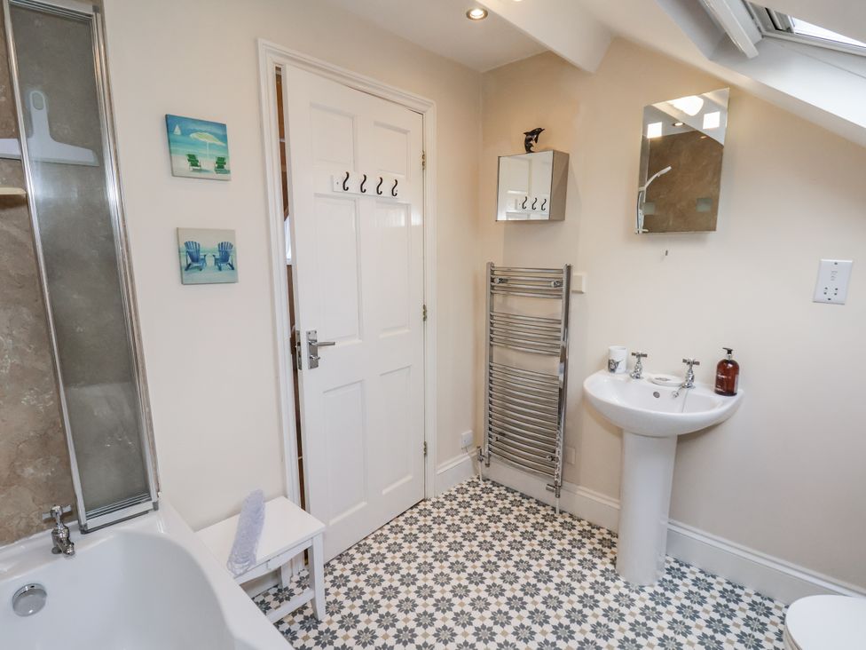 A bathroom with a bathtub, shower, sink, and towel rail at 2 High Stakesby Cottages in Whitby