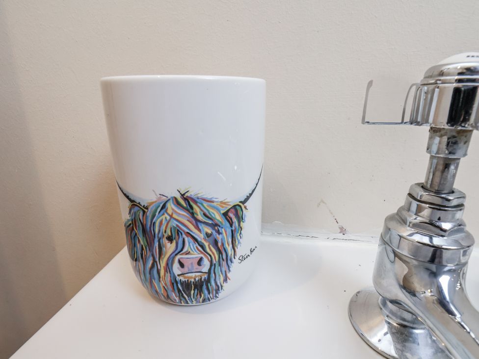 A mug with a highland cow illustration next to a sink at 2 High Stakesby Cottages in Whitby