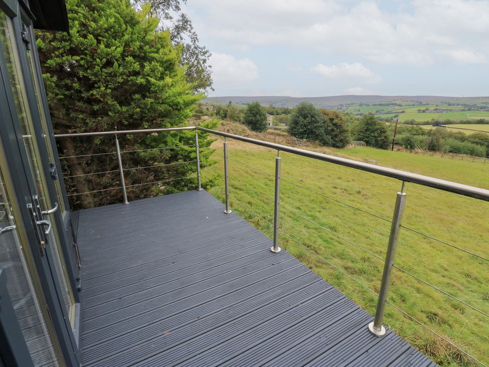An outdoor deck area with railing and view of hills at John's Folly