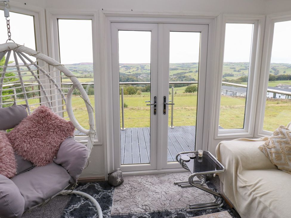A sunroom with a hanging chair and a couch at John's Folly