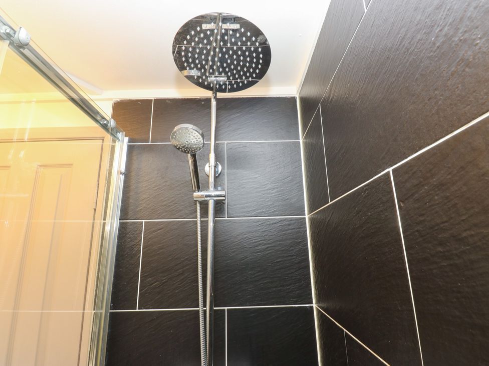 A shower with slate tiles and a shower head at John's Folly
