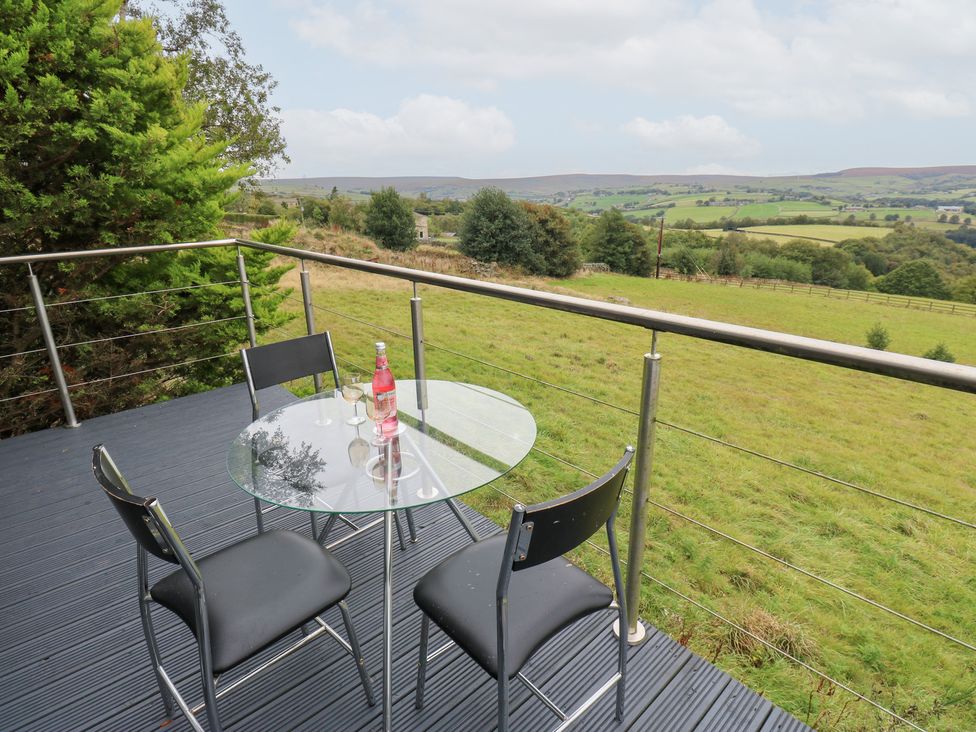 An outdoor seating area with chairs and a table overlooking a grassy landscape at John's Folly