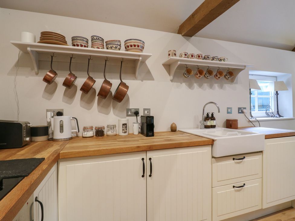 A kitchen with shelves holding pots and mugs at The Piggery in Maidstone