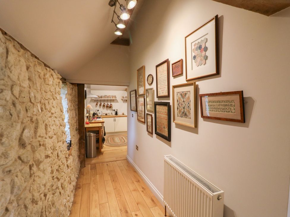 A hallway with framed artwork and a stone wall at The Piggery in Maidstone