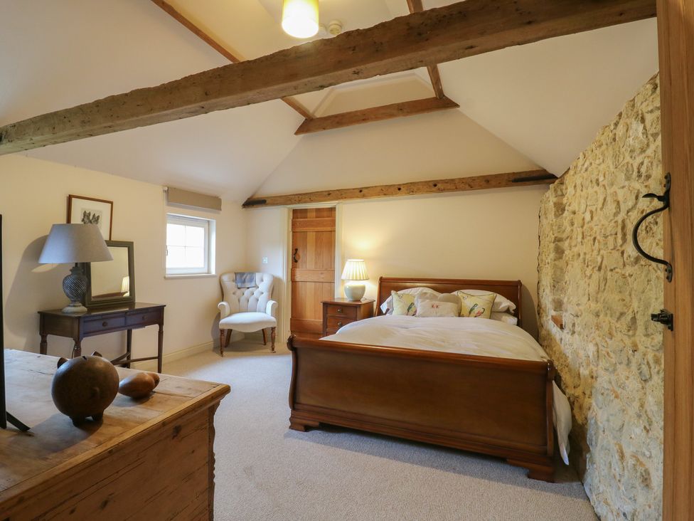 A bedroom with a bed, lamp, chair, and dresser at The Piggery in Maidstone