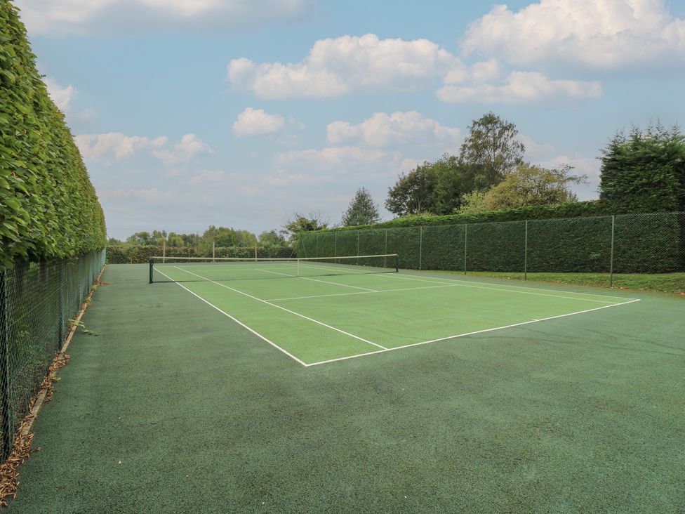 A tennis court surrounded by a hedge at The Piggery in Maidstone
