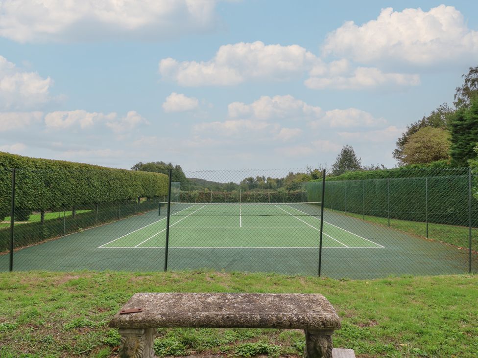 A tennis court surrounded by fences and hedges at The Piggery Maidstone