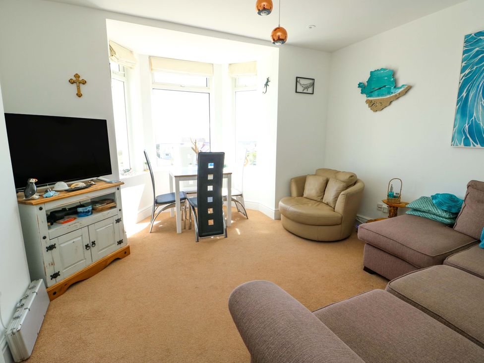 A living room with a television and dining area at 19 Cliff Apartments in Trearddur Bay