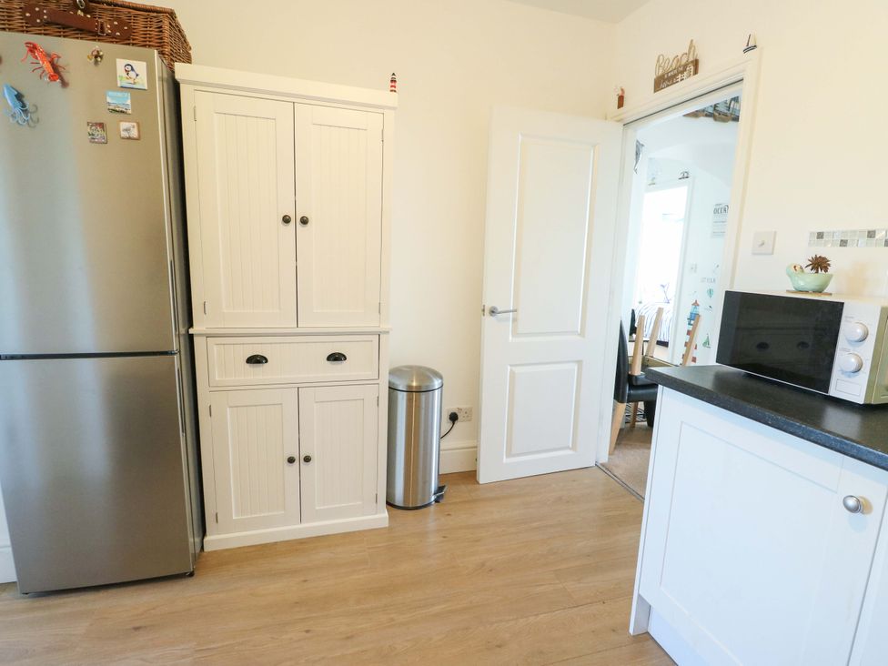 A kitchen with a refrigerator and cupboard at 19 Cliff Apartments in Trearddur Bay