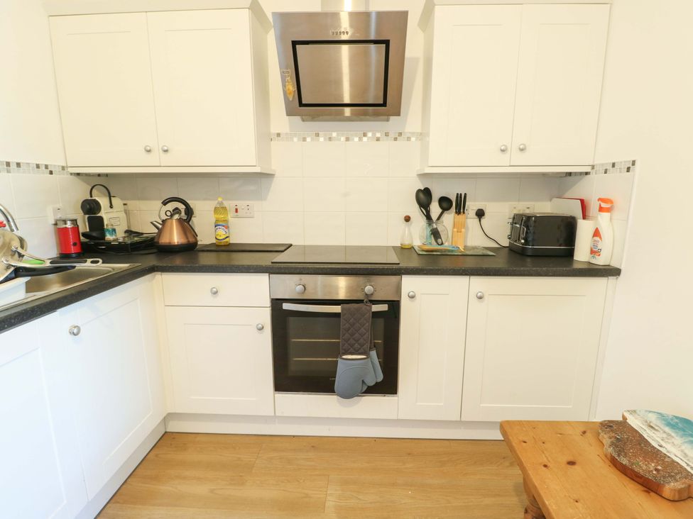 A kitchen with cabinets, sink, stove, and appliance at 19 Cliff Apartments Trearddur Bay