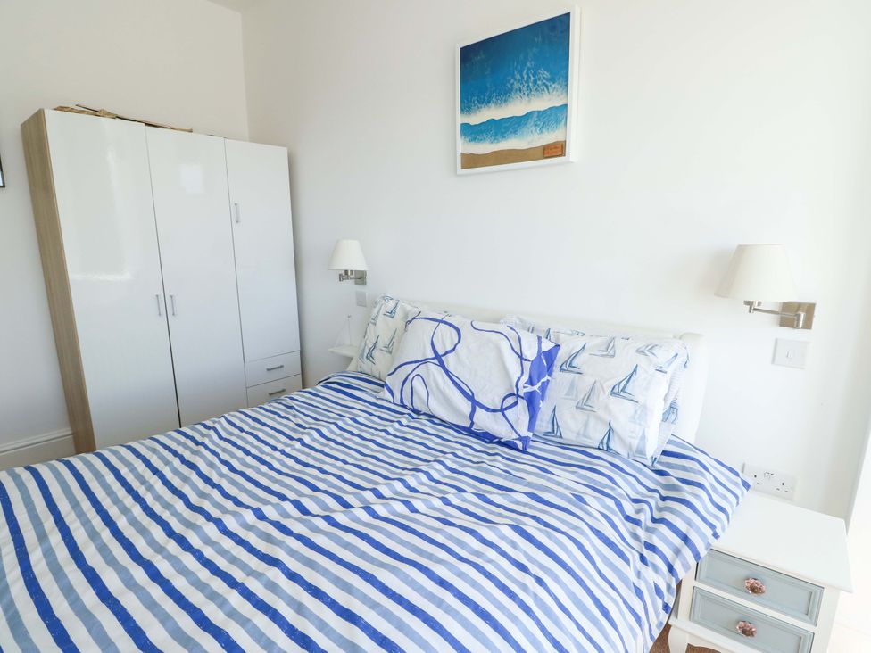 A bedroom with a bed and wardrobe at 19 Cliff Apartments in Trearddur Bay