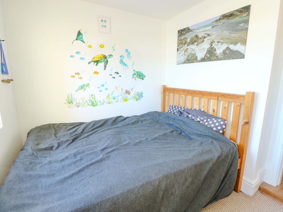 A bedroom with a bed and wall art at 19 Cliff Apartments in Trearddur Bay