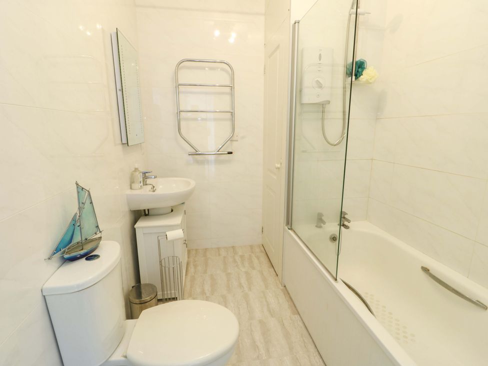 A bathroom with a sink, toilet, bathtub, and shower at 19 Cliff Apartments in Trearddur Bay