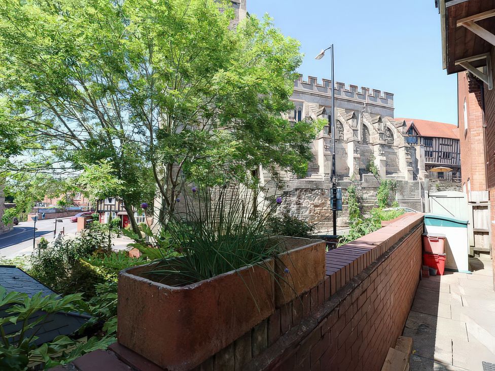 A view of trees and a brick wall with a road at 3 Leycester Court in Warwick