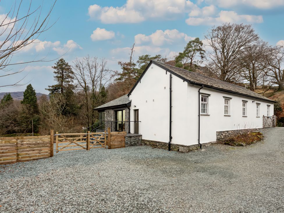 A house with a gravel driveway and trees around it at The Old Bunkhouse in Grasmere