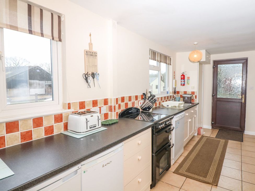 A kitchen with various appliances and a window at Court House Farmhouse, Charmouth