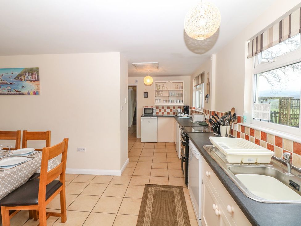 A kitchen with a dining table and appliances at Court House Farmhouse in Charmouth