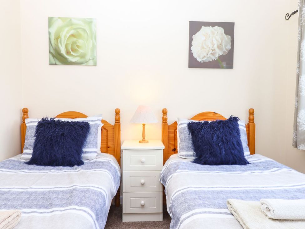 A bedroom with two beds and a lamp on a nightstand at Court House Farmhouse in Charmouth