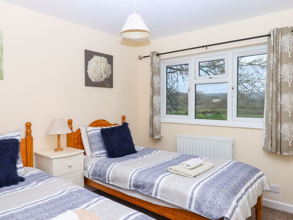 Two single beds with a bedside table and window at Court House Farmhouse, Charmouth