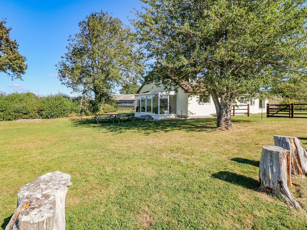 An outdoor view of a house with a table and trees at Court House Farmhouse in Charmouth