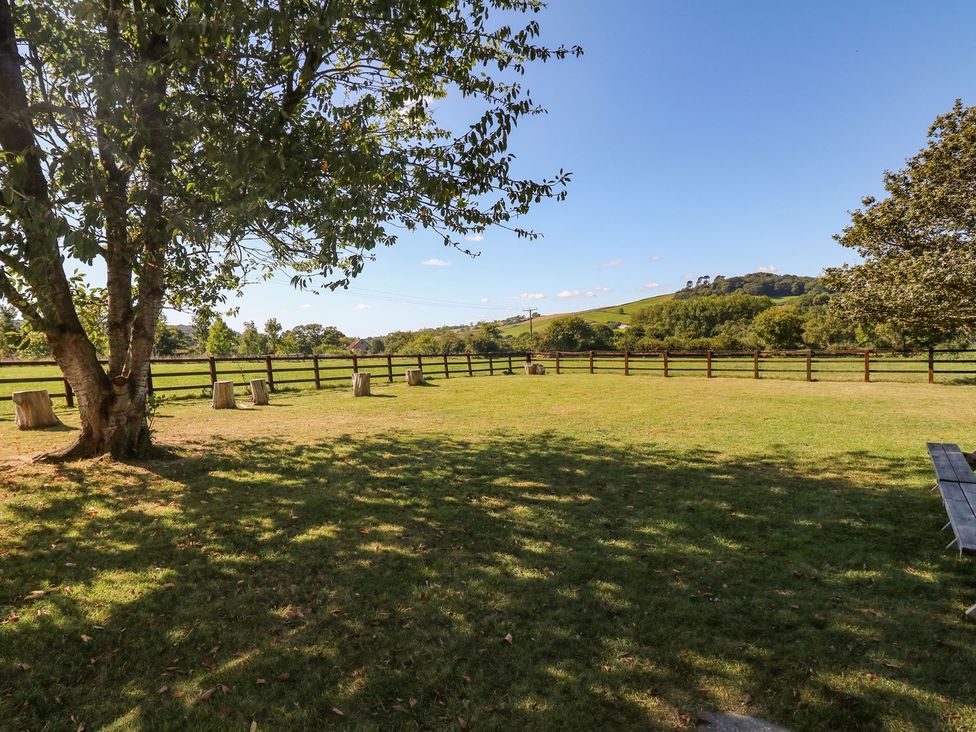 An outdoor garden with a tree and seating at Court House Farmhouse Charmouth