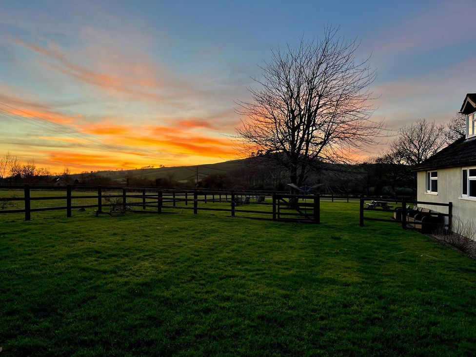 A landscape view with a house and trees at Court House Farmhouse in Charmouth