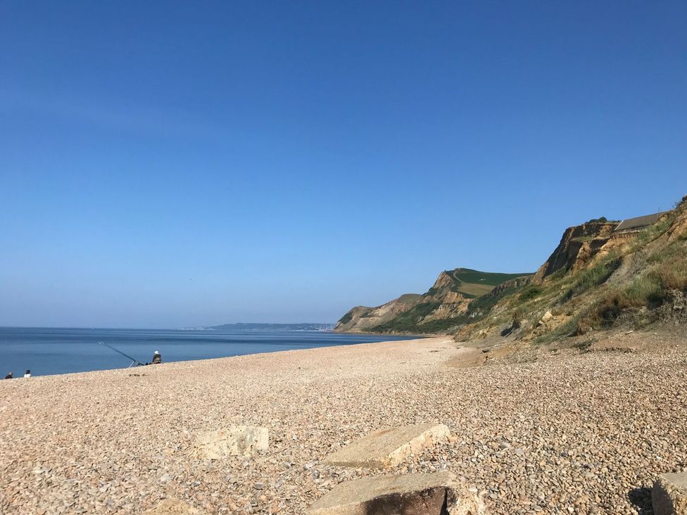 A beach with pebbles and a person fishing at Court House Farmhouse in Charmouth