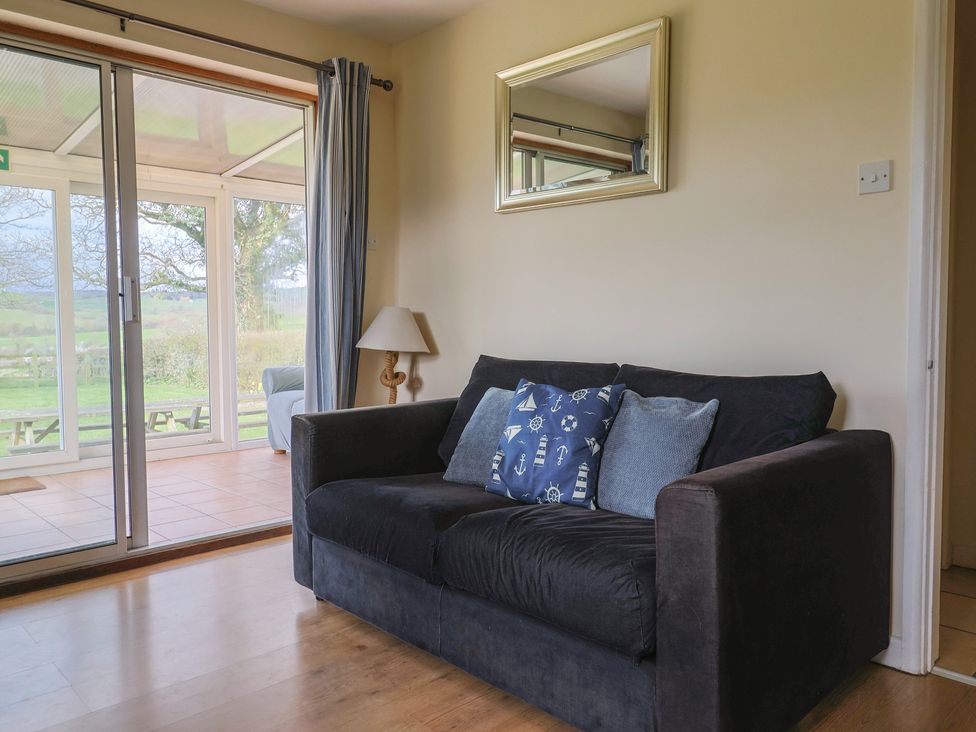 A living room with a sofa and sliding door at Court House Farmhouse in Charmouth