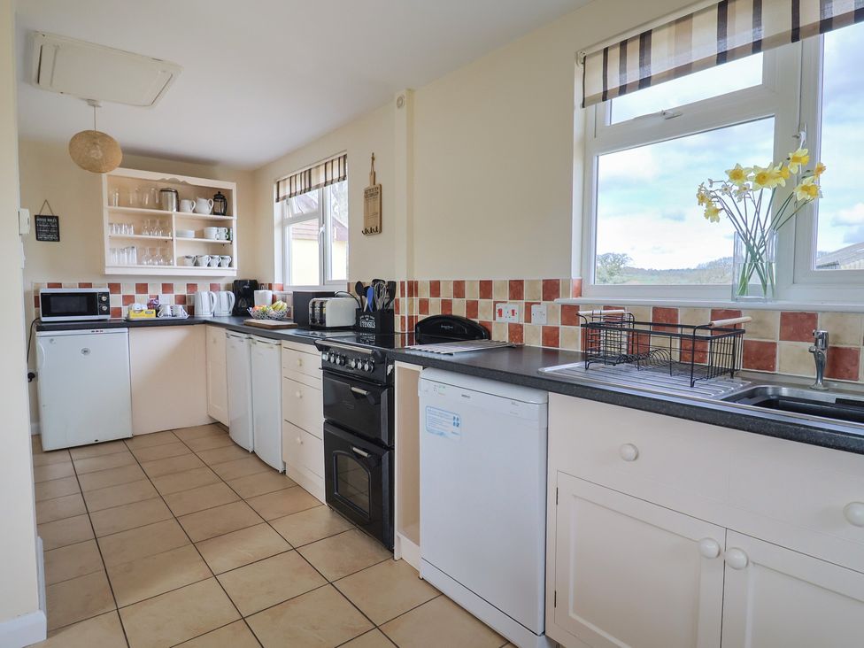 A kitchen with a stove and refrigerator at Court House Farmhouse in Charmouth