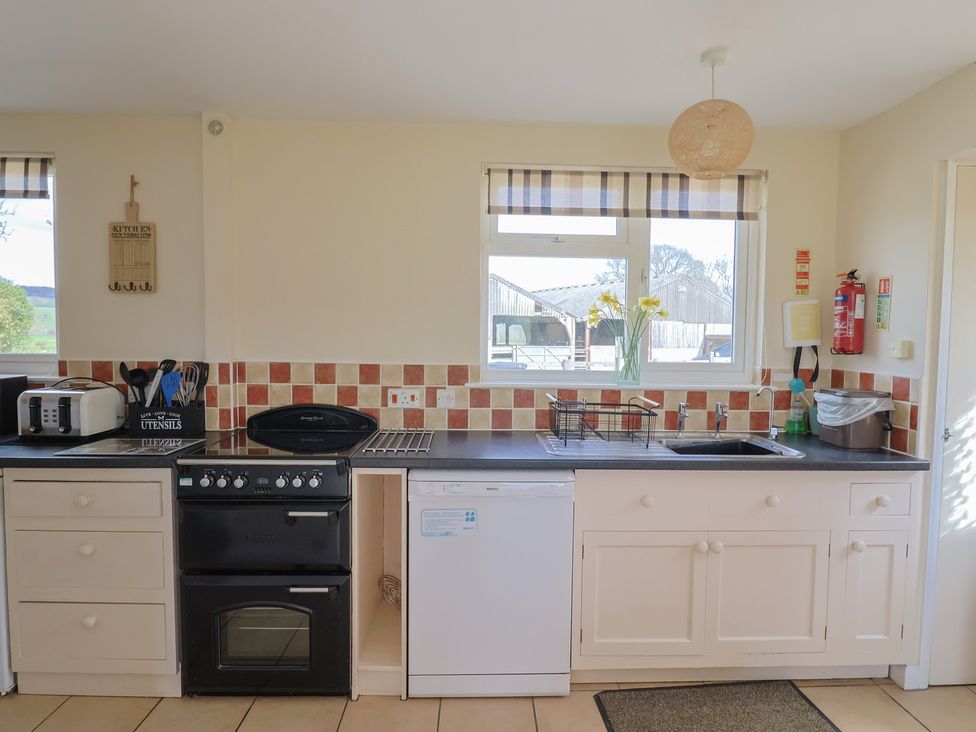 A kitchen with a sink, oven, and dishwasher at Court House Farmhouse in Charmouth