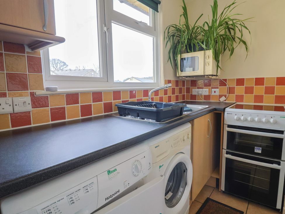 A kitchen with sink, washing machine, microwave and oven at Court House Farmhouse in Charmouth