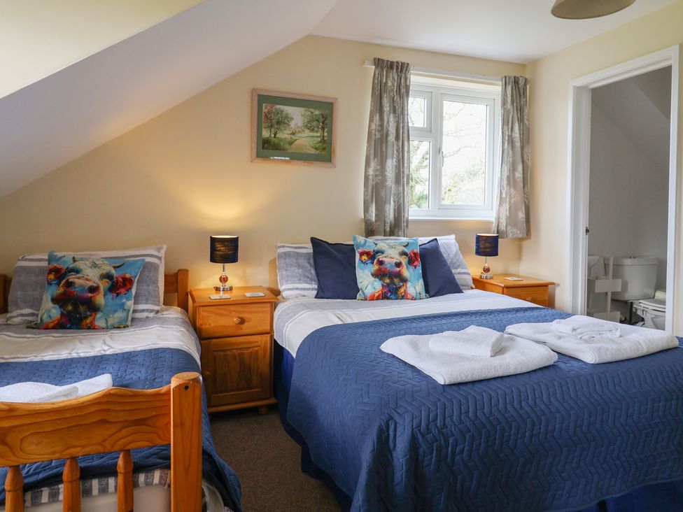 A bedroom with two beds and a window at Court House Farmhouse Charmouth