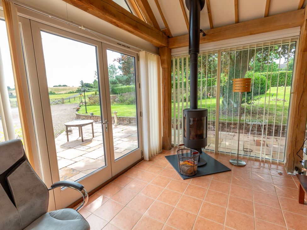 A room with a stove and a chair at Nature's Lodge in Kidderminster